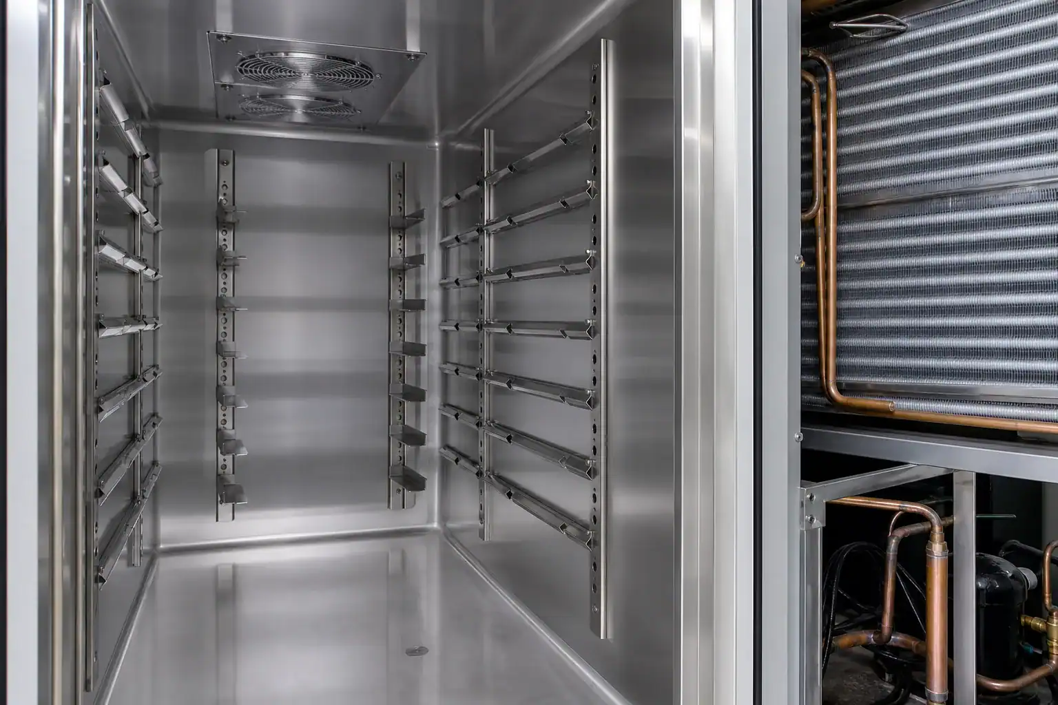 Inside view of a stainless steel commercial refrigeration unit with multiple racks.