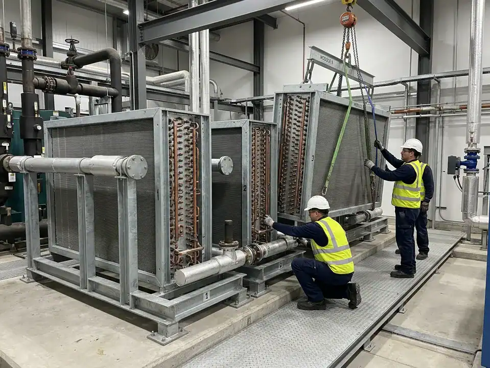 Technicians installing large industrial refrigeration unit in a facility.
